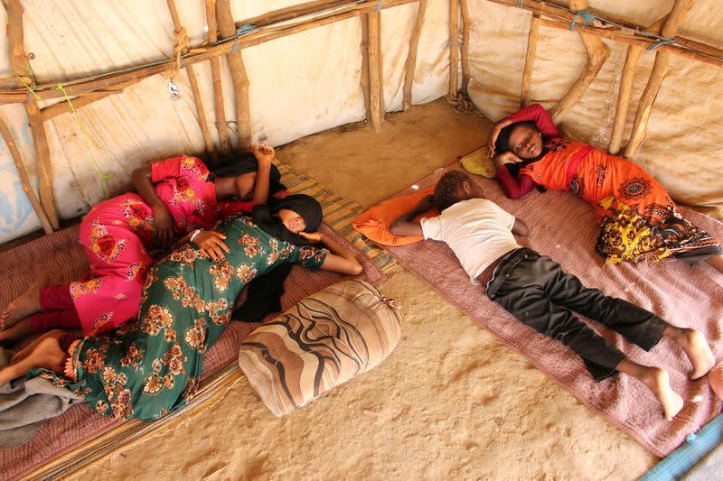 Children lie in their family's hut as they recuperate from dengue fever at a camp for internally displaced in Abs of Hajja province