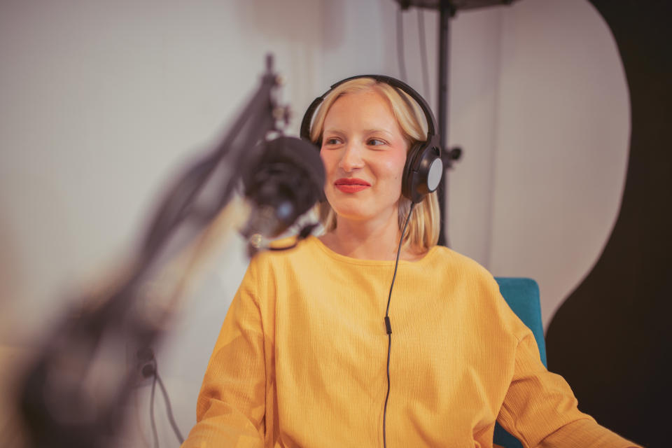 A smiling woman wearing headphones at a microphone