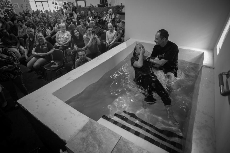 Pastor Mozzy Delpeche guides a rider into a bath as he baptises her during a weekly service at the CMA Midvaal chapter in Vereeniging (EPA)