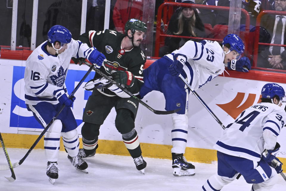 Minnesota's Jake Middleton, center, in action against Toronto's Mitchell Marner, left, and Matthew Knies during the NHL Global Series Sweden ice hockey match between Toronto Maple Leafs and Minnesota Wild at Avicii Arena in Stockholm, Sweden, Sunday, Nov. 19, 2023.(Claudio Bresciani/TT via AP)