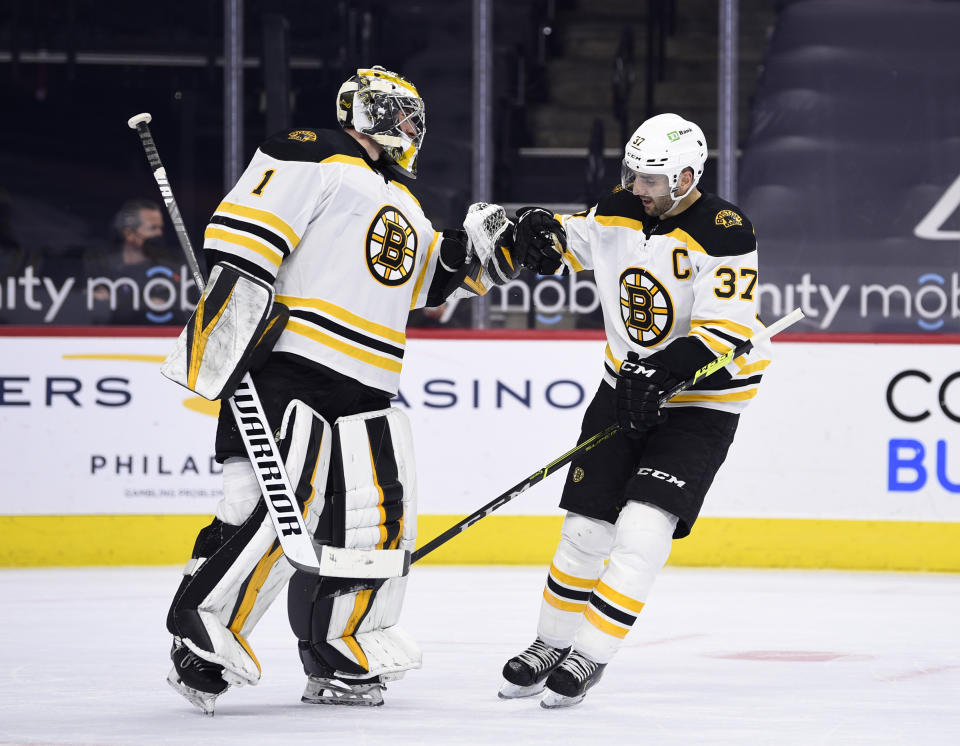 Boston Bruins' Patrice Bergeron, right, high-fives Jeremy Swayman after Bergeron scored a goal during the first period of an NHL hockey game against the Philadelphia Flyers, Tuesday, April 6, 2021, in Philadelphia. (AP Photo/Derik Hamilton)