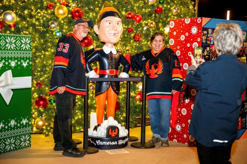 Jerry and Kathy Olearnick of La Quinta stand next to the Cameron Hughes bobble head prior to puck drop at Acrisure Arena in Palm Desert, Calif., on Wed., Dec. 13, 2023.