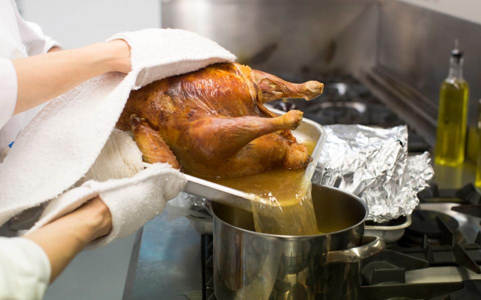 Taking the roasting juices from the cooked turkey and putting them in a new pot - JEFF GILBERT