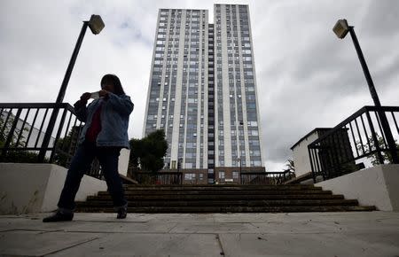 A woman walks away from the Dorney Tower residential block, from where residents were evacuated as a precautionary measure following concerns over the type of cladding used on the outside of the buildings on the Chalcots Estate in north London, Britain, June 25, 2017. REUTERS/Hannah McKay