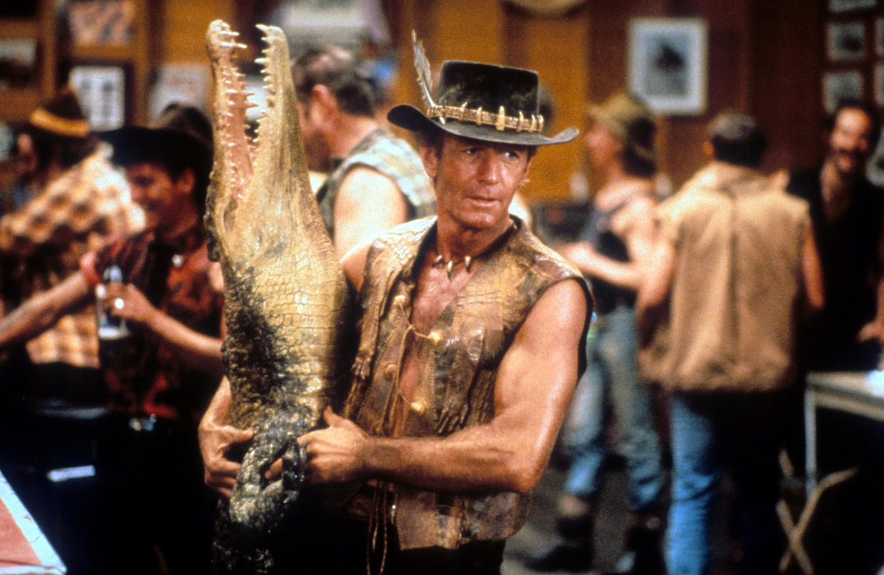 Paul Hogan carrying dead crocodile in a bar in a scene from the film 