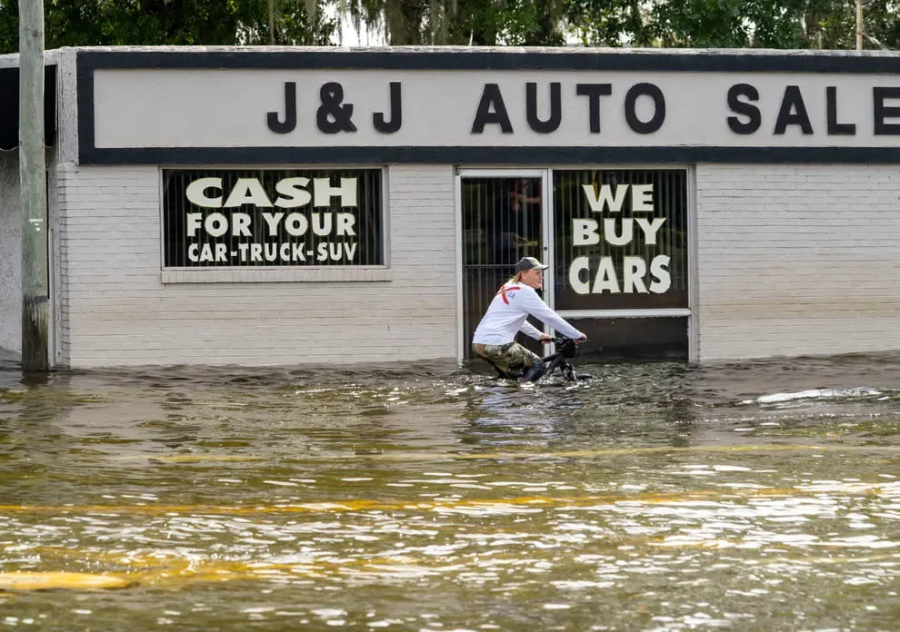 A man bikes through floodwaters in Crystal River on Aug. 30 after Hurricane Idalia made landfall to the north, in Florida's Big Bend.