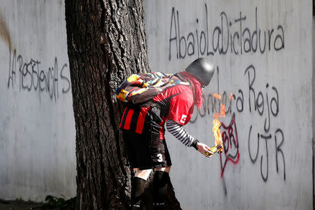 A demonstrator prepares to use a petrol bomb at a rally during a strike called to protest against Venezuelan President Nicolas Maduro's government in Caracas, Venezuela July 26, 2017. The graffiti reads "The resistances, down with the dictatorship, red flag". REUTERS/Carlos Garcia Rawlins