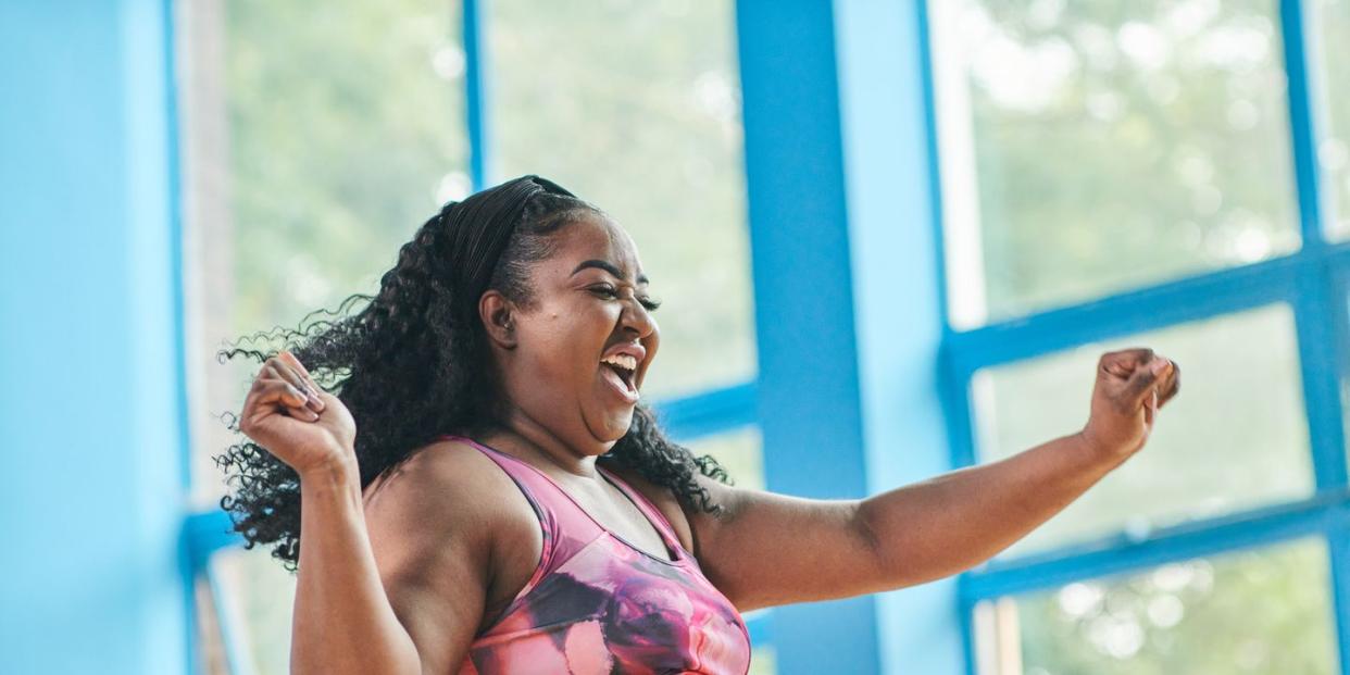 woman in colourful gym attire dancing and smiling