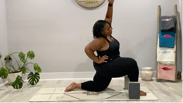 Woman kneeling on a yoga mat leaning her left arm over to the right in a side bend