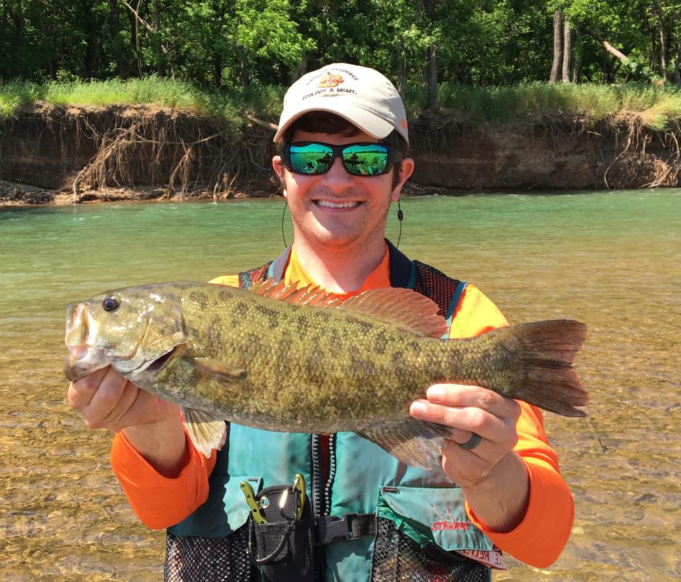 Andrew Taylor, an assistant professor of fisheries biology at the University of Central Oklahoma, holds a Neosho smallmouth bass from the Baron Fork near Tahlequah, a fish native to the Ozarks in northeastern Oklahoma.