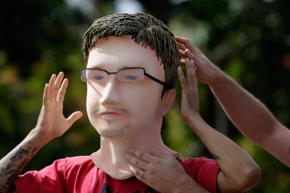 A activist adjusts his mask of former NSA analyst Edward Snowden before a protest demanding Brazil's government grant Snowden asylum, outside the foreign ministry in Brasilia, Brazil, Thursday, Feb. 13, 2014. Last year, Snowden revealed that the United States collected data on billions of telephone and email conversations in Latin America's biggest country, including Brazilian President Dilma Rousseff's communications with aides. (AP Photo/Eraldo Peres)