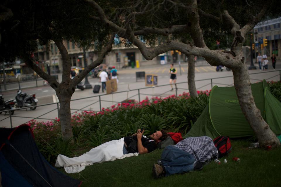 Joan Pelisa, 36, spends the night at the Catalunya square during a protest to mark the anniversary of the "Indignados" movement in Barcelona, Spain, Sunday May 13, 2012. Spaniards angered by increasingly grim economic prospects and unemployment hitting one out of every four citizens protested in droves Saturday in the nation's largest cities, marking the one-year anniversary of a spontaneous movement that inspired similar anti-authority demonstrations across the planet. (AP Photo/Emilio Morenatti)