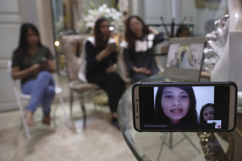 A relative of Dr. Michael Robert Marampe is seen through a mobile phone screen as she attends an online memorial service to mark the 40th day since Marampe passed away due to COVID-19 in Jakarta, Indonesia, on June 5, 2020. Marampe knew what he wanted to be since he was a kid: a doctor and a pianist. He became both, and his passion for music even led him to Tri Novia Septiani - a woman he never got to marry because he got the coronavirus. Marampe became one of dozens of doctors the coronavirus has claimed so far in Indonesia. (AP Photo/Tatan Syuflana)