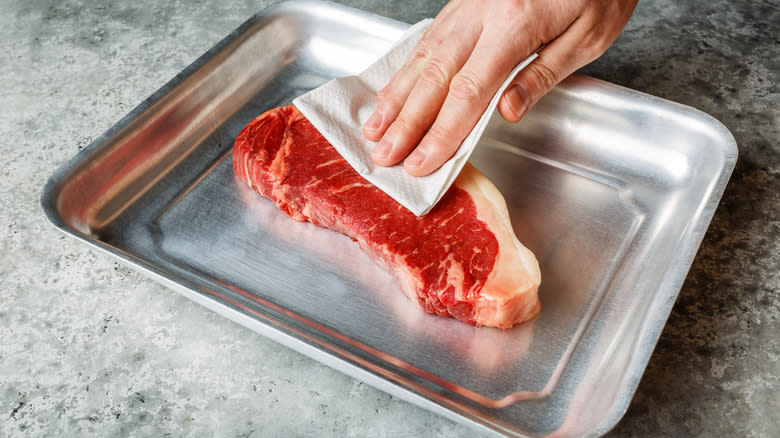 Patting steak dry with towel