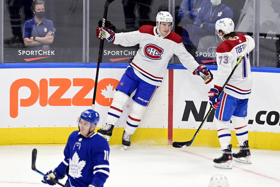 Montreal Canadiens center Nick Suzuki (14) celebrates a goal with teammate Tyler Toffoli (73) as Toronto Maple Leafs left wing Zach Hyman (11) skates by during the first period of an NHL hockey game Wednesday, Jan. 13, 2021 in Toronto. (Frank Gunn/The Canadian Press via AP)