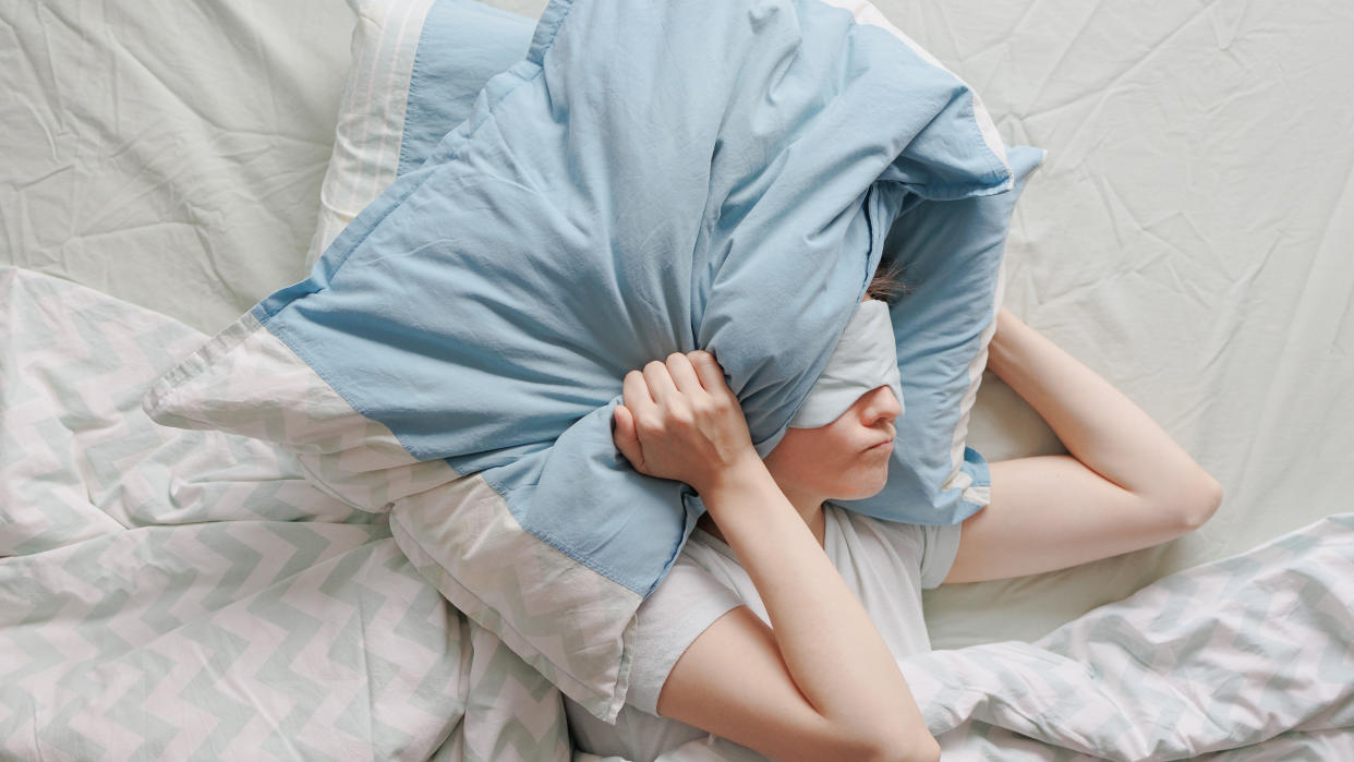  A woman holds a blue pillow over her face 