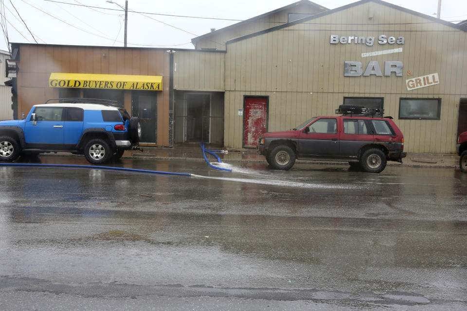 Hoses pump water out the front door of the Bering Sea Bar Grill in Nome, Alaska, on Saturday, Sept. 17, 2022, after the city was flooded when a severe storm hit the community. Just hours after this photo was made, the bar and grill situated just a half block from the Bering Sea burned to the ground. Interim city manager Bryant Hammond said the cause of the fire and whether it was related to the storm were not immediately known. (AP Photo/Peggy Hagerstrom)