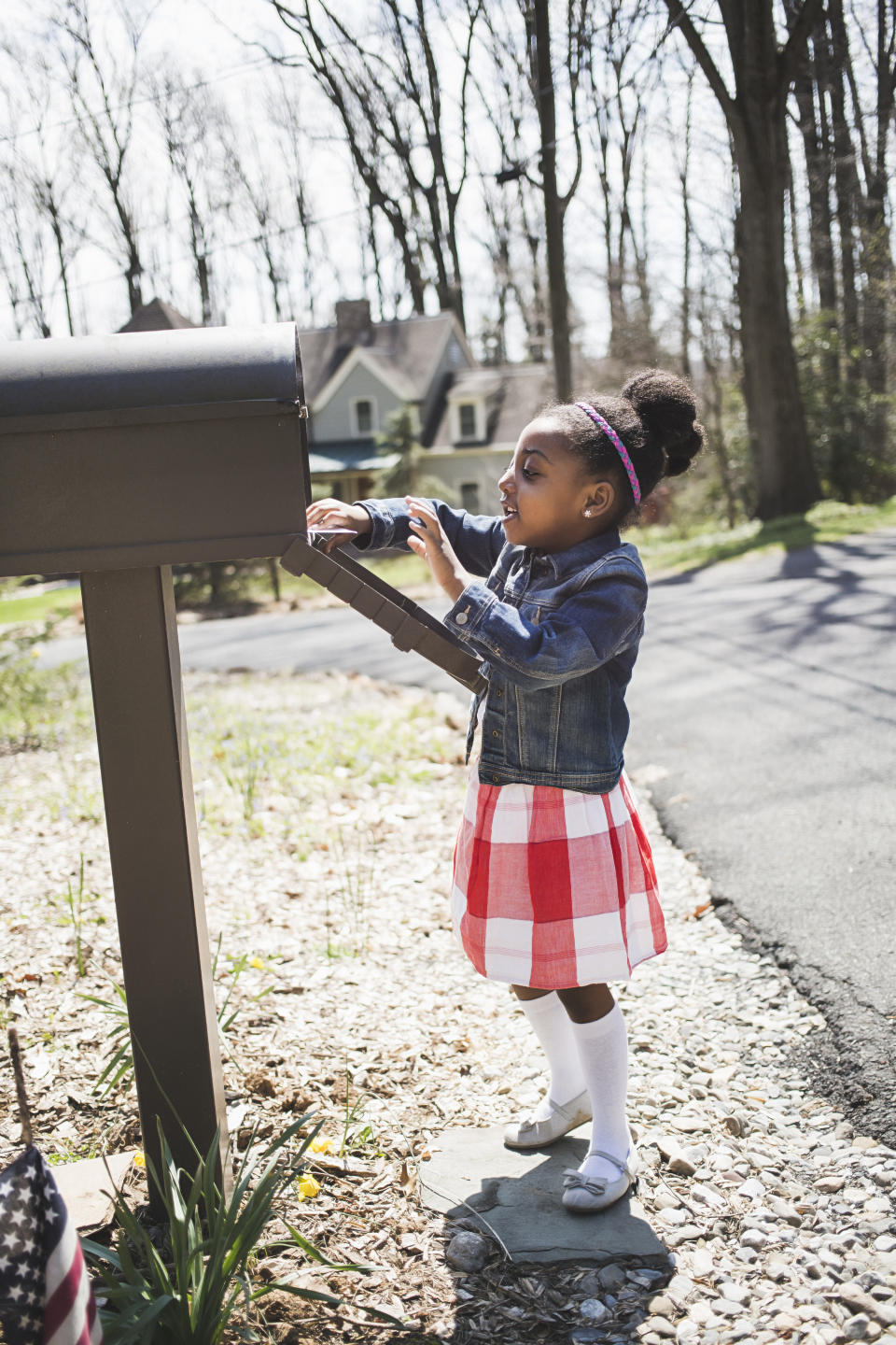 A young girl looks inside her family's mail box