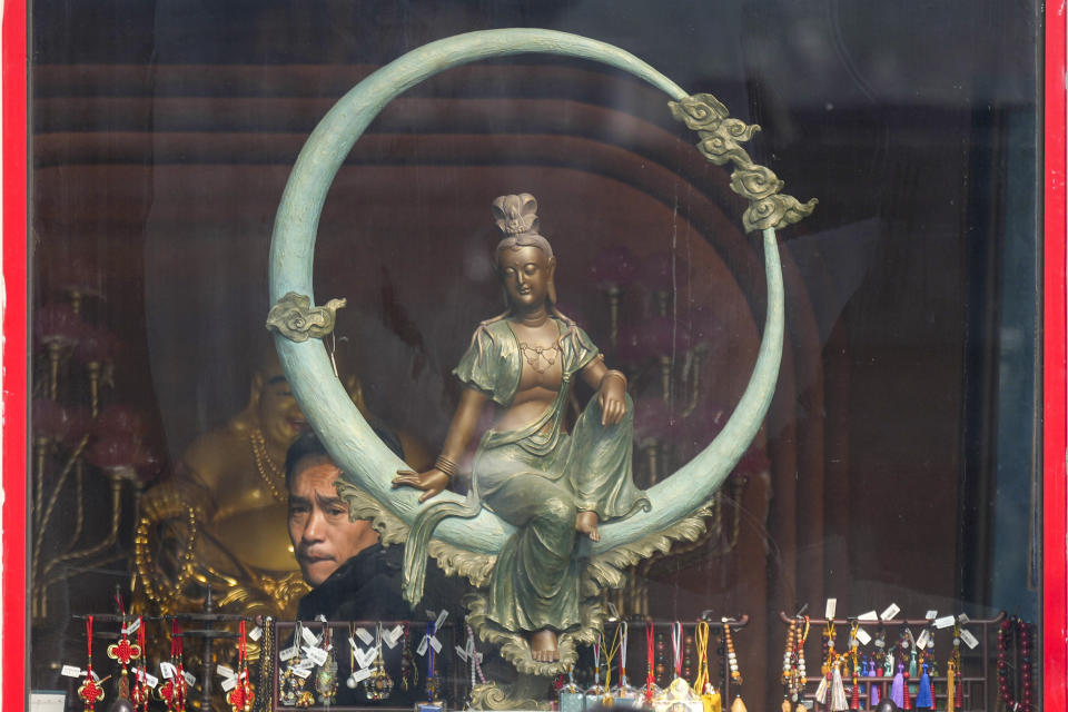 A man shops near a statue at a souvenir store in Beijing, China, Friday, April 12, 2024. (AP Photo/Tatan Syuflana)