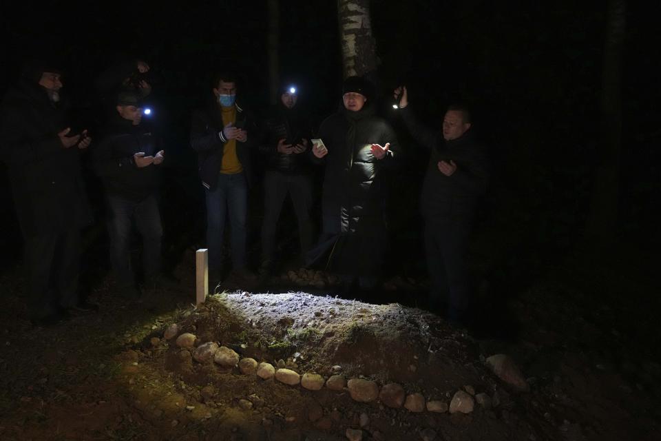 People of a Muslim congregation community pray at the grave of young Syrian man, Ahmed al-Hassan in Bohoniki near Sokolka, Poland, Monday, Nov. 15, 2021. The 19-year-old man died in late October in a river in this freezing, forested buffer zone. The authoritarian Belarusian regime in Minsk has for months been orchestrating a flow of migrants across its border into the three European Union nations, which form the eastern flank of both the 27-nation EU and NATO. In response, the three have been reinforcing their borders. (AP Photo/Matthias Schrader)
