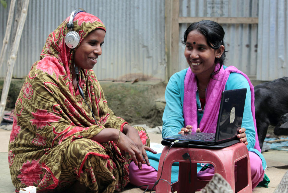 In this Sept. 30, 2012, photo, Bangladeshi Info Lady Mehedi Akthar Misty, right, helps Amina Begum, 45, to talk with her husband with Skype at Jharabarsha, in a remote impoverished farming village in Gaibandha district, 120 miles (192 kilometers) north of capital Dhaka, Bangladesh. Begum had never seen a computer until a few years ago, but now she’s on Skype regularly with her husband. A woman on a bicycle brings the Internet to her. Dozens of “Info Ladies” bike into remote Bangladeshi villages with laptops and Internet connections, helping tens of thousands of people - especially women - get everything from government services to chats with distant loved ones. (AP Photo/A.M. Ahad)