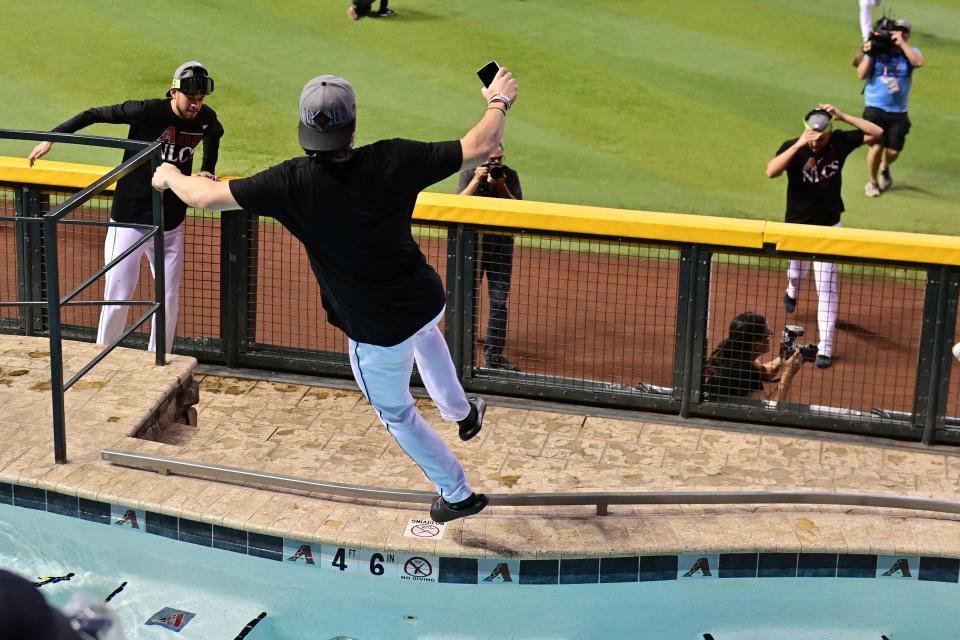 Diamondbacks left fielder Corbin Carroll jumps into a pool with cell phone and all.