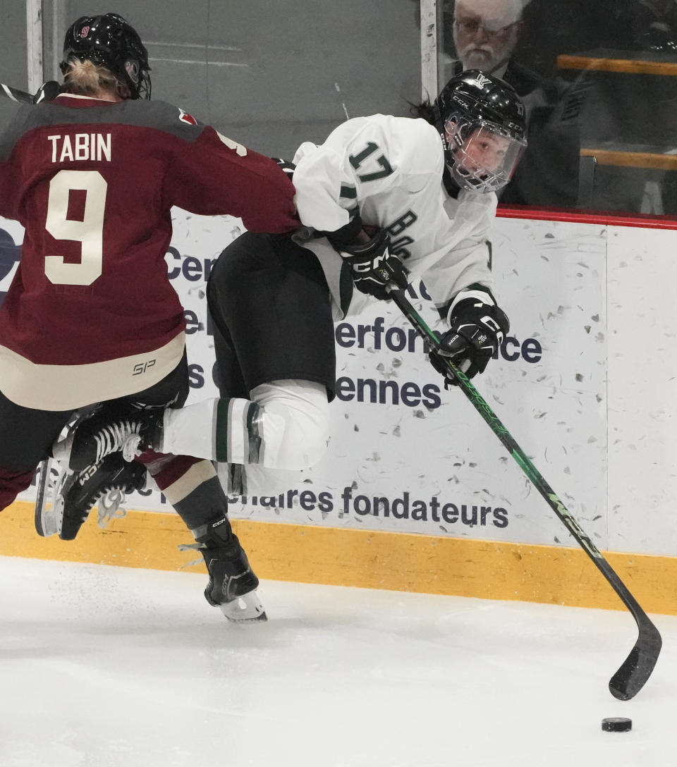 FILE - Montreal's Kati Tabin (9) checks Boston's Taylor Girard (17) into the boards as they battle for the puck during the first period of a PWHL hockey game in Montreal on Saturday, Jan. 13, 2024. The Professional Women's Hockey League has no designs on expanding its six-team base for the foreseeable future. That isn't stopping the first-year league from exploring potential markets by holding neutral site games in Detroit and Pittsburgh this weekend. (Christinne Muschi/The Canadian Press via AP, File)