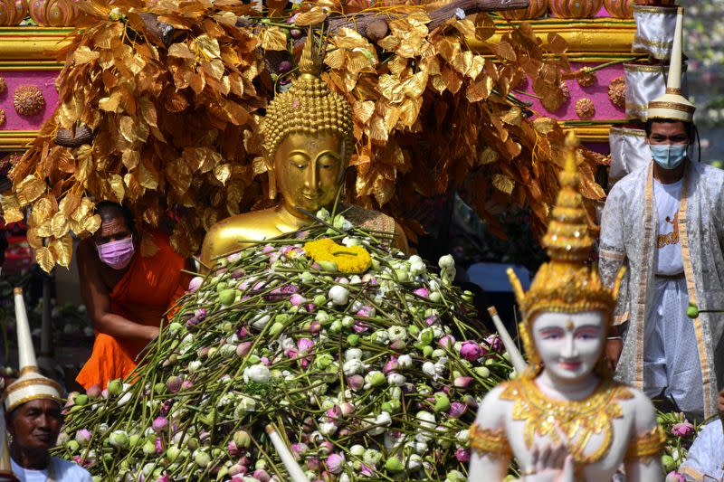 Una estatua dorada de Buda flota a lo largo de un río, recibiendo flores de los creyentes, durante el festival de la flor de loto, para marcar el final de la cuaresma budista, en Samut Prakan, Tailandia