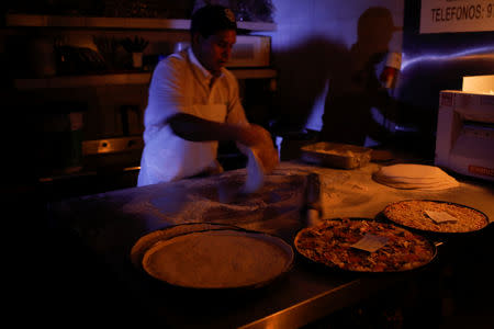 A man cooks with candlelight and lanterns at a pizzeria during a second day of blackout in Caracas, Venezuela March 9, 2019. REUTERS/Marco Bello