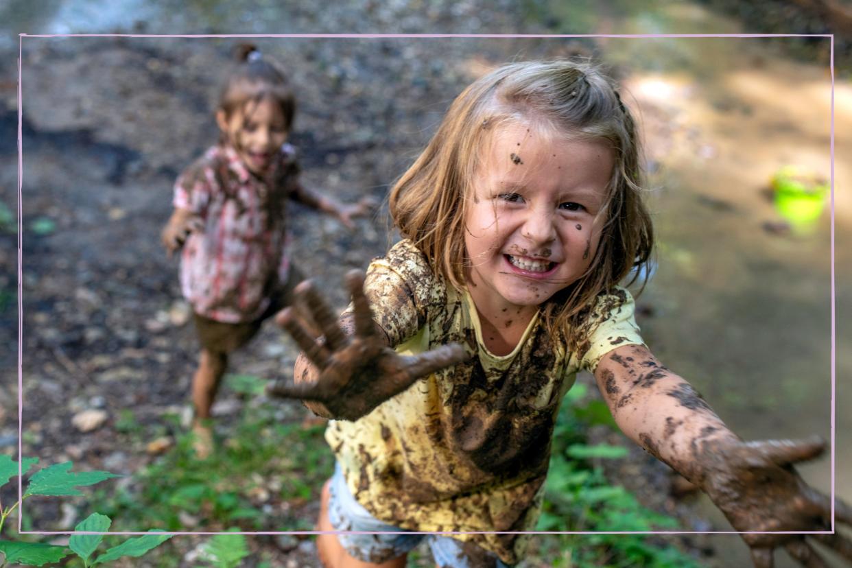  Smiling children engaging in messy play - they are covered in mud, playing outdoors. 