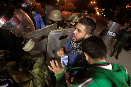 A human rights observer overcome by tear gas argues with military police during a protest by supporters of Salvador Nasralla, presidential candidate for the Opposition Alliance Against the Dictatorship, demanding the official presidential election results, outside the warehouse of the Supreme Electoral Tribunal in Tegucigalpa, Honduras November 30, 2017. REUTERS/Jorge Cabrera