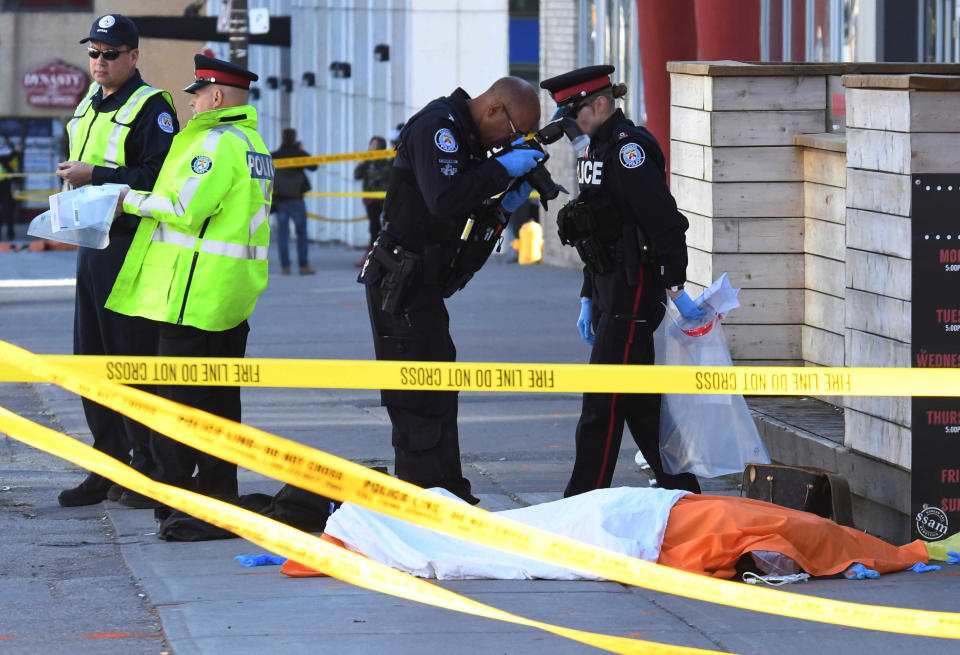 <p>A police officer takes a picture of a covered body after a van struck multiple people at a major intersection northern Toronto, Ontario, Canada, April 23, 2018. (Photo: Saul Porto/Reuters) </p>