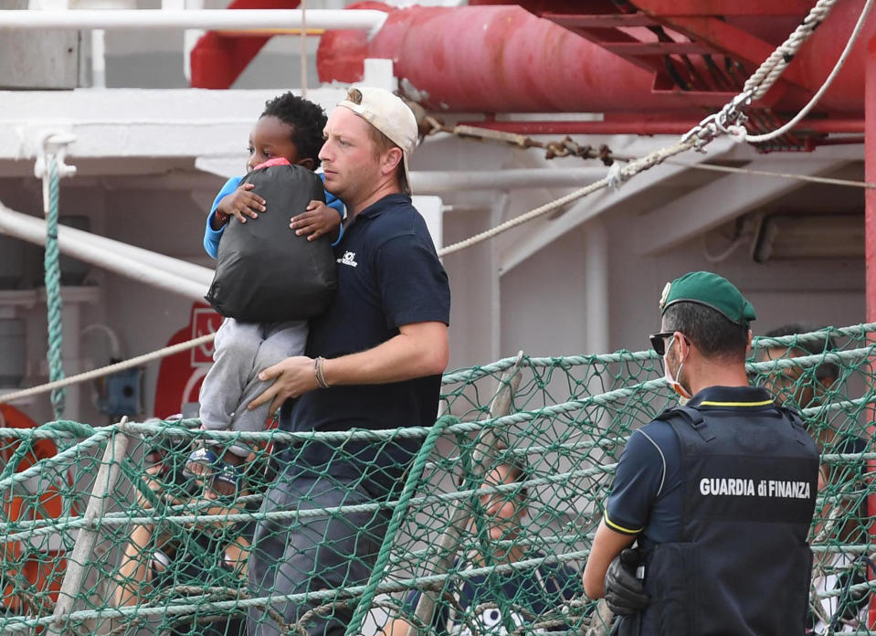 A migrant child is carried as he disembarks the Ocean Viking, docked at the Sicilian port of Messina, southern Italy, Tuesday, Sept. 24, 2019. The humanitarian ship has docked in Sicily, Italy, to disembark 182 men, women and children rescued in the Mediterranean Sea after fleeing Libya. (Carmelo Imbesi/ANSA via AP)