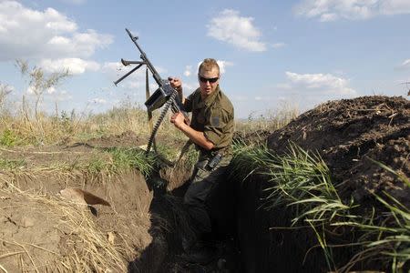 A Ukrainian serviceman with a machine gun changes his position in a trench after seeing something suspicious at a military camp in Luhansk region August 21, 2014. REUTERS/Valentyn Ogirenko