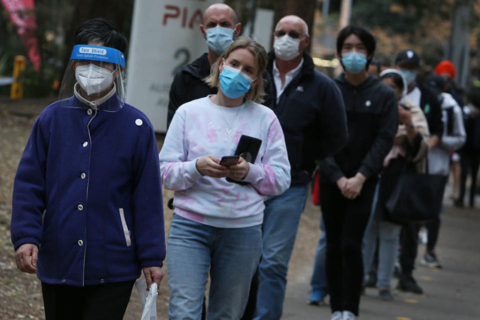 Men and women in masks queue for a vaccine in Sydney. 