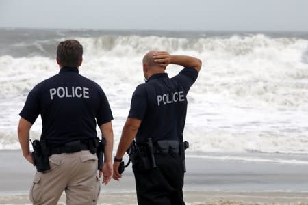 Police officers survey the increasingly rough surf as Hurricane Dorian approaches, in Carolina Beach, North Carolina