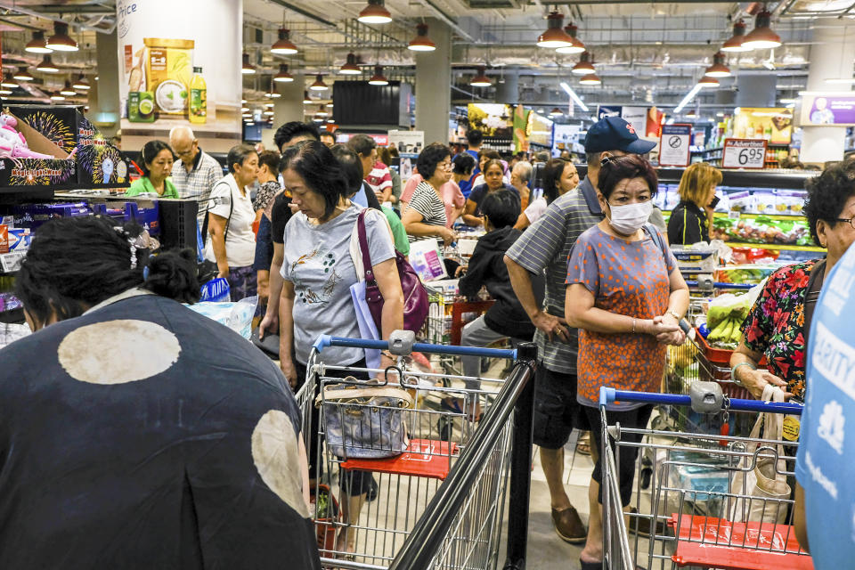 Shoppers wait in line to pay at a supermarket in Singapore, Tuesday, Mar. 17, 2020. Singaporeans were seen buying food supplies in supermarkets following neighboring Malaysia's announcement of a nationwide lockdown due to the coronavirus to begin Wednesday which could affect the flow of food supplies to the city state. (AP Photo/Ee Ming Toh)