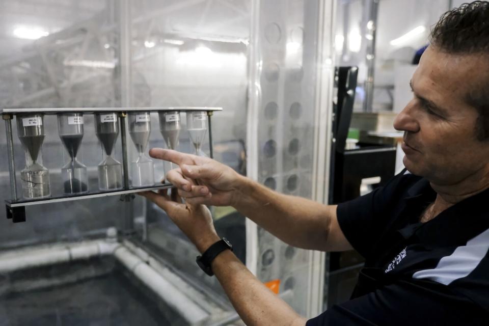 A man shows an hourglass-like structure holding different types of dust.