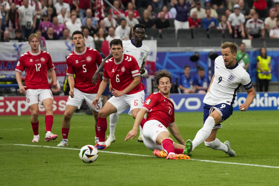 Euro 2024 England player Harry Kane (9) shoots past Denmark player Joachim Andersen (center) to score a goal during a Group C match between Denmark and England at the Euro 2024 soccer championships in Frankfurt, Germany, Thursday, June 20, 2024. (AP Photo/Themba Hadebe)