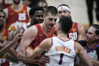 Referee David Guthrie, right, struggles to keep Denver Nuggets center Nikola Jokic, back, from fighting with Phoenix Suns guard Devin Booker in the second half of Game 4 of an NBA second-round playoff series Sunday, June 13, 2021, in Denver. (AP Photo/David Zalubowski)