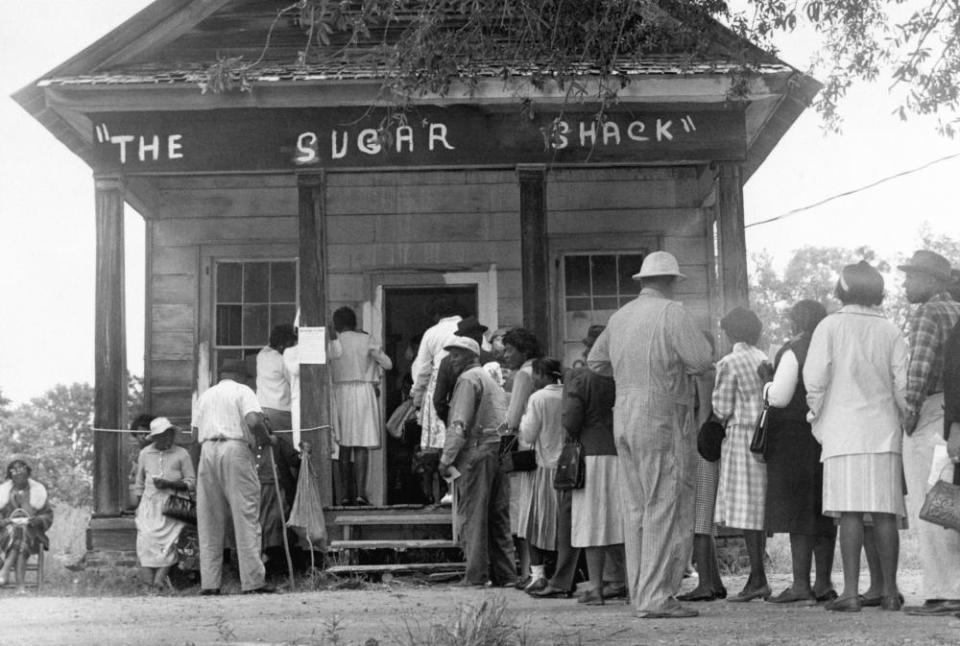 African American voters, able to vote for the first time in rural Wilcox County, Alabama, line up in front of a polling station at The Sugar Shack, a local general store. After the passage of the federal voting rights law in 1965, there were almost twice as many black voters than whites.