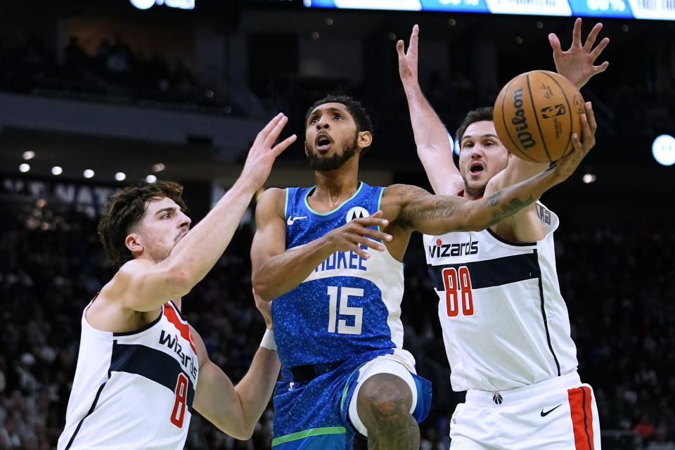 Milwaukee Bucks' Cameron Payne (15) shoots between Washington Wizards' Deni Avdija (8) and Danilo Gallinari (88) during the first half of an NBA basketball In-Season Tournament game Friday, Nov. 24, 2023, in Milwaukee. (AP Photo/Aaron Gash)