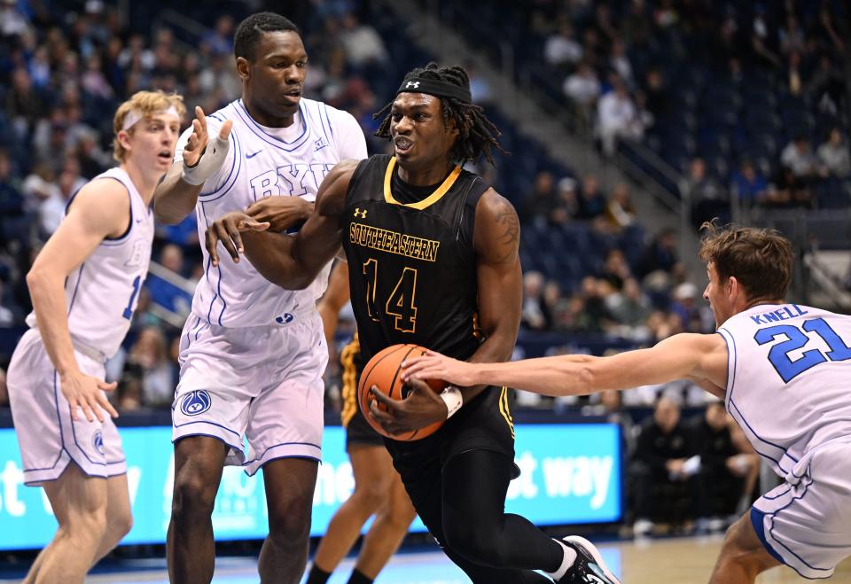 Southeastern Louisiana Lions forward Dylan Canoville (14) drives between Brigham Young Cougars forward Atiki Ally Atiki (4) and Brigham Young Cougars guard Trevin Knell (21) as BYU and SE Louisiana play at the Marriott Center in Provo on Wednesday, Nov. 15, 2023. | Scott G Winterton, Deseret News