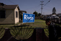 In this Thursday, Sept. 6, 2018, photo, a student walks past a lawn sign supporting Robert Rivas, a Democratic candidate for California's 30th State Assembly District in Salinas, Calif. Few cities exemplify California's housing crisis better than Salinas, an hour's drive from Silicon Valley and surrounded by farm fields. It's one of America's most unaffordable places to live, and many residents believe politicians lack a grip on the reality of the region's housing crisis. (AP Photo/Jae C. Hong)