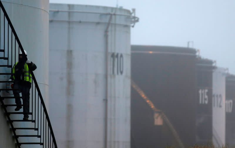 FILE PHOTO: A worker walks up the stairs on the side of an oil tank at the Total refinery in Grandpuits