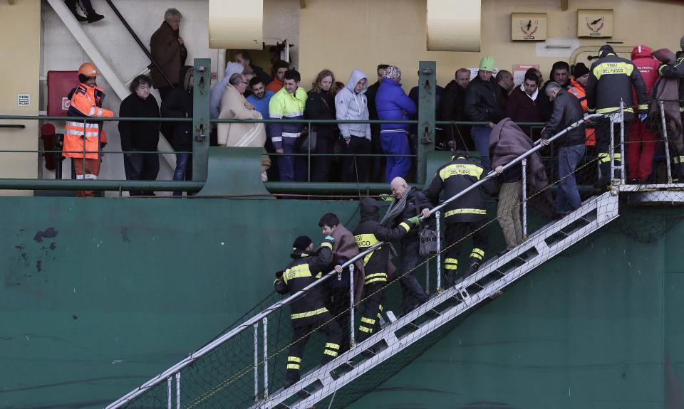 Firefighters help passengers leave the "Spirit of Piraeus" cargo container ship as they arrive in Bari harbour, after the car ferry Norman Atlantic caught fire in waters off Greece December 29, 2014. Rescue teams working through the night have pulled 265 people off a stricken car ferry which caught fire off the coast of Greece but more than 200 are stranded on board, the Italian navy said on Monday. REUTERS/Yara Nardi ( ITALY - Tags: DISASTER MARITIME)