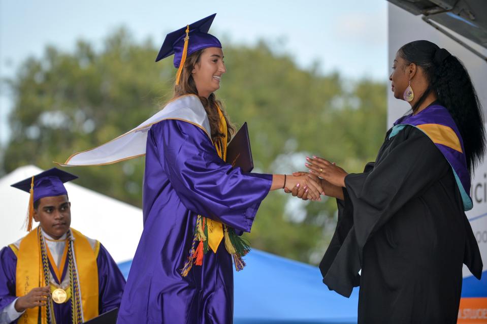 Fort Pierce Central Valedictorian Presley Murray, center, is congratulated by Principal Monarae Miller-Buchanan during the start of Wednesday's commencement ceremony at Lawnwood Stadium in Fort Pierce.