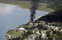 Smoke rises from a house deliberately set on fire, days after part of the ground it was resting on collapsed into Lake Whitney, Texas June 13, 2014. REUTERS/Brandon Wade