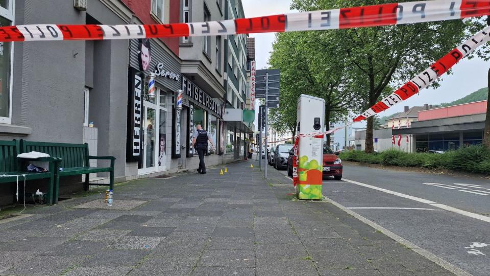 Ein Polizist geht hinter einem Absperrband der Polizei zu einem Friseursalon (Bild: dpa)