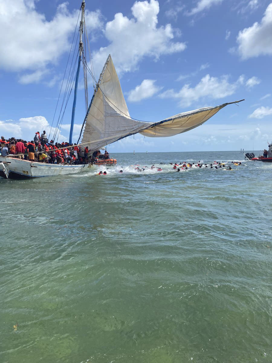 In this image posted on the USCGSoutheast Twitter page, rescue crews safely transfer people from a grounded vessel believed to be carrying migrants, to U.S. Coast Guard ships, Saturday, Aug. 6, 2022, off the coast of Key Largo, Fla., near the gated community of Ocean Reef. (Courtesy of U.S. Coast Guard via AP)